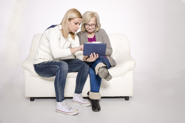 Young woman and her mother sitting on a white couch.