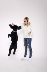 Young woman playing with a black poodle.