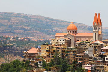 Big number of buildings at the mountains with one big church rising high between them.