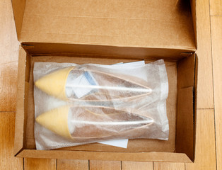 Pair of new yellow women shoes in the plastic white box waiting to being unboxed and measured