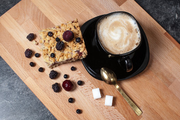 .cup of cappuccino with homemade pastries pie raspberry jam and berries on a wooden board.