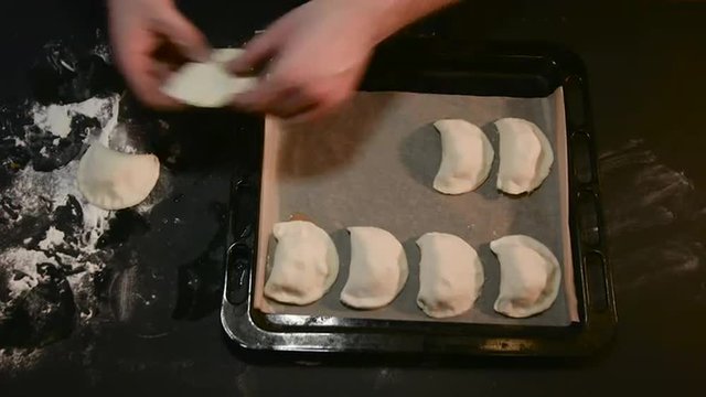 Man Puts the Pies on a Baking Sheet For Baking