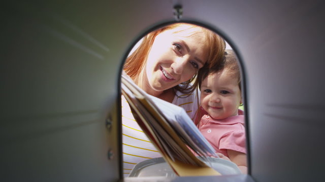 Woman and daughter get mail from mailbox