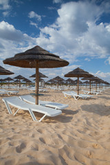 Different parasols and sun loungers on the empty beach on Tavira