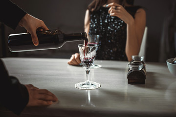 Beautiful young couple with glasses of red wine in luxury restaurant