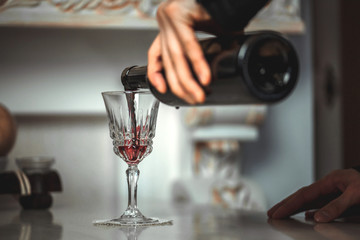 man pours bottle with red wine in a beautiful glass