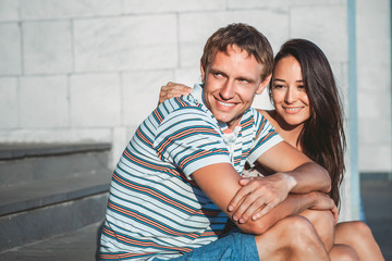 beautiful young couple sitting on the steps and laugh. The concept of joy and happiness