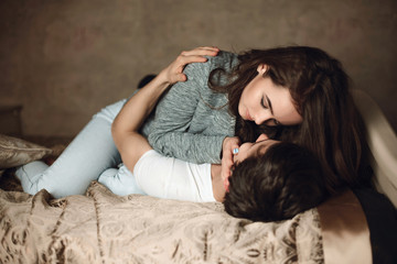 beautiful brunette girl lies on top on guy on the bed