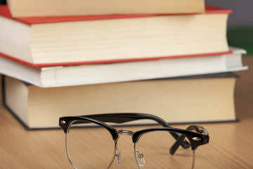 Pair of eyeglasses next to a pile of books