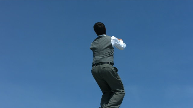 Businessman back flipping in sky, slow motion