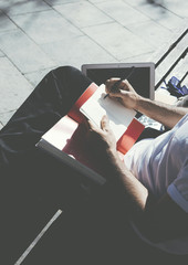 Photo man sitting city park and texting message notepad. Studying at the University, working project, campus. Using book, generic design laptop. Vertical