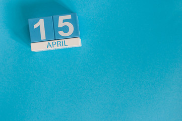 April 15th. Tax Day. Image of april 15 wooden color calendar on blue background.  Spring day, empty space for text