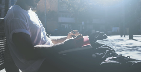 Photo man sitting student campus and texting message notepad. Studying at the University, working project, preparing exam. Using book, generic design laptop. Wide mock up, sunlights