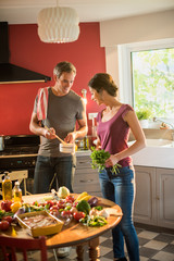Trendy couple cooking vegetables from the market in the kitchen