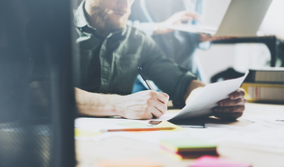 Photo bearded account manager working with new project. Generic design notebook on wood table.  Analyze plans hands, keyboard. Blurred background, film effect