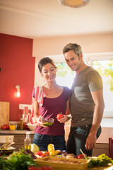 Happy couple cooking together vegetables in retro red kitchen