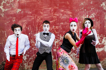 Four armed mimes standing on a red wall.
