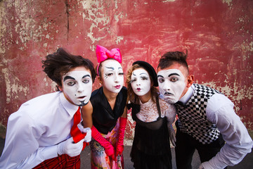 Four mimes surprised look on a red wall.