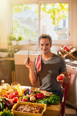 Smiling grey haired man is about to cut a tomato with a knife.