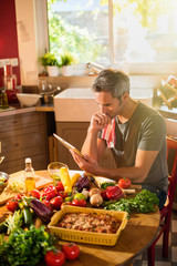 Grey haired man looking at vegetables recipes on a tablet