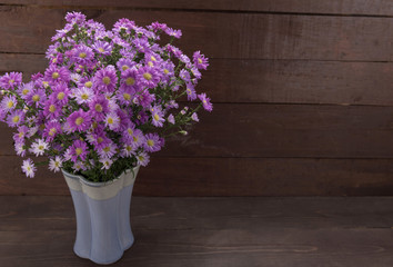 Purple cutter flowers in the vase, on the wooden background