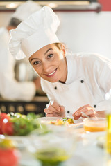 Portrait of a woman chef putting herbs on a  plateful