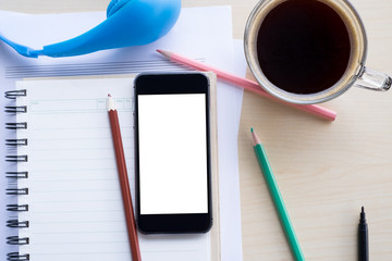 top view blank screen of mobile phone on notebook and wooden des