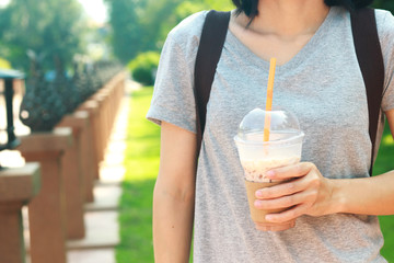 Asian women holding Iced coffee with milk in plastic glass.