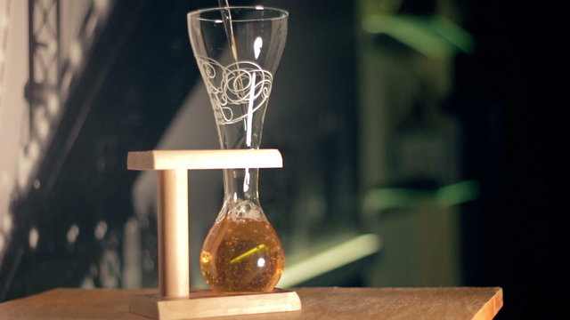 Elite light beer is being poured into a curved glass