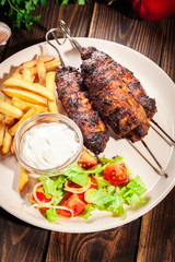 Grilled shish kebab served with fried chips and salad