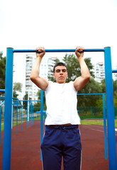 Obraz premium Muscular man doing pull-ups on horizontal bar