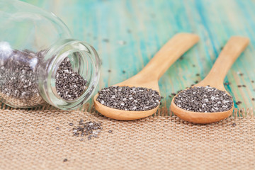 chia seeds spilling out of glass bottle on wood table