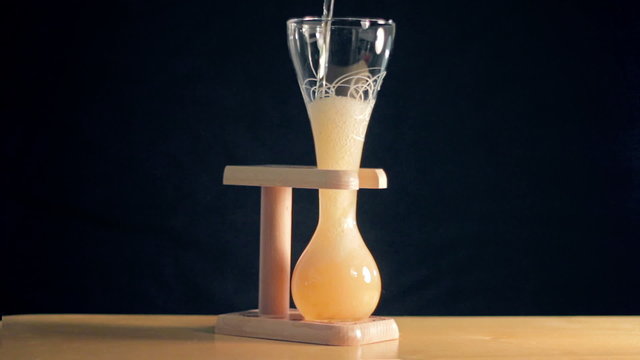 Elite light beer is being poured into a curved glass