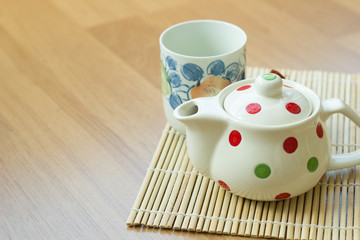 Tea pot and cup on wooden table.