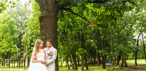 Young wedding couple enjoying romantic moments outside on a summer park