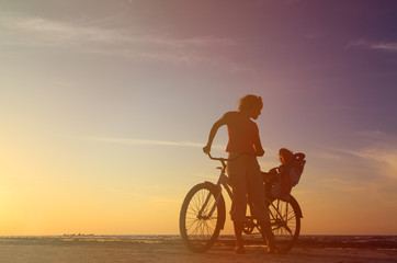 Fototapeta na wymiar Silhouette of mother and baby biking at sunset