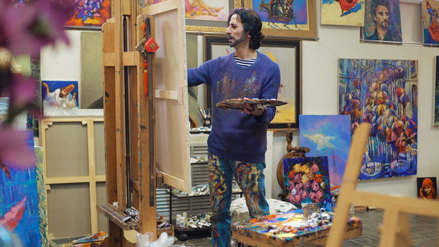 Senior painter holding a palette. creates in his studio