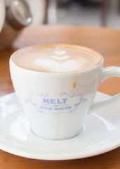 Cup of Art Latte coffee on the wooden desk