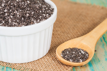 Nutritious chia seeds in bowl and spoon on a wooden