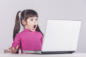 Little girl reacts while using a laptop. Internet safety concept