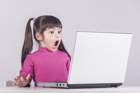 Little Girl Reacts While Using A Laptop. Internet Safety Concept