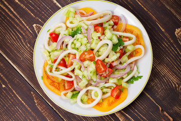 Squid, tomato, onion and greens salad. View from above, top studio shot