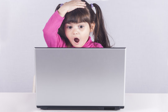 Little girl reacts while using a laptop. Internet safety concept