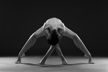 Fototapeta premium Nude yoga. Beautiful sexy body of young woman on black background