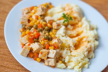Healthy vegetarian cuisine with tofu with colorful roast vegetables including carrot, peas and maize served with mashed potatoes. Selective focus