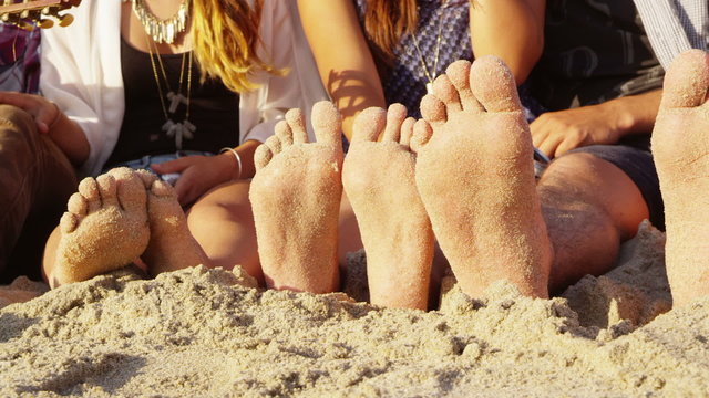 Group of young people with feet in sand, closeup