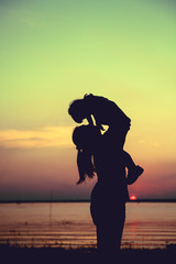 Fototapeta premium Silhouette of mother and child enjoying the view at riverside. 