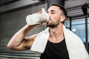 Muscular man drinking protein shake - 105413389