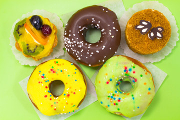 Two brown and round cakes. Three glazed donuts