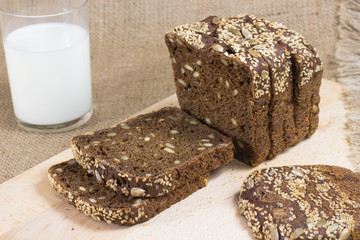 Black bread cut into slices. A glass of milk